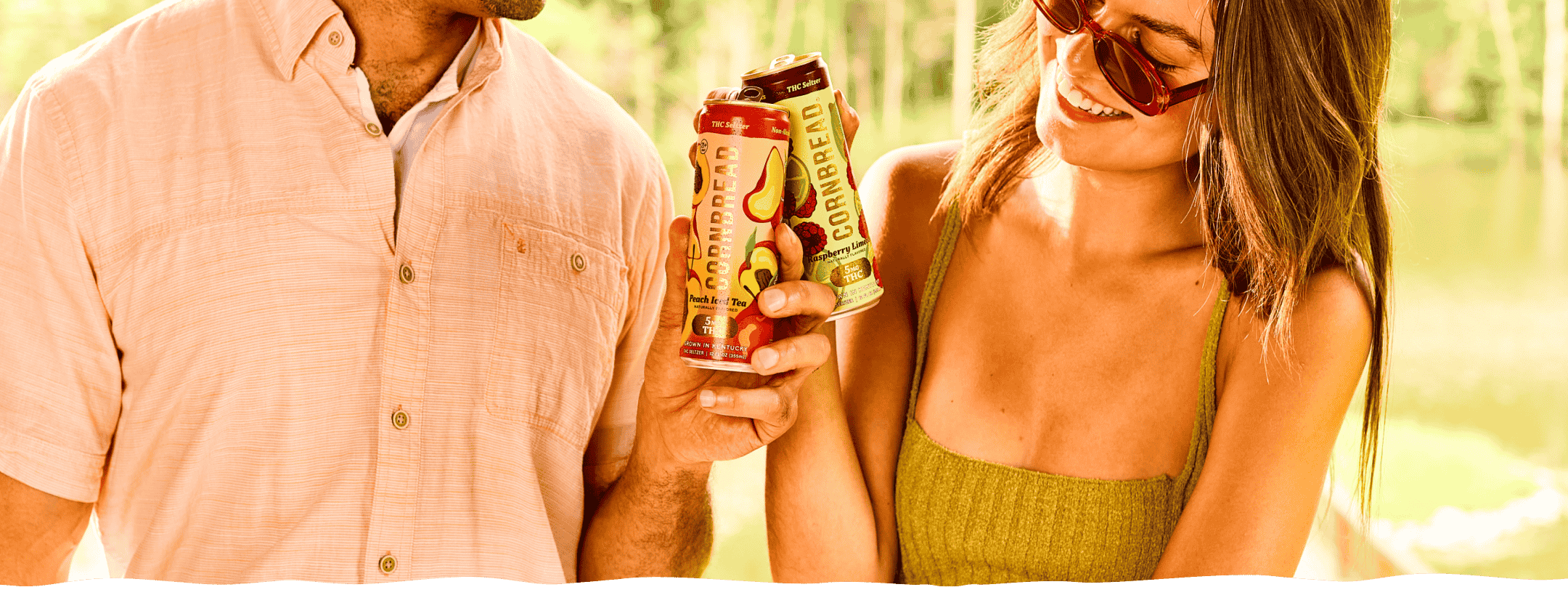 Two people cheersing with Cornbread Hemp Raspberry Limeade and Peach Iced Tea THC Seltzers