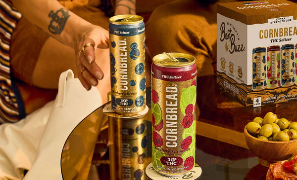 Cornbread THC edibles cans on a table with a person's hand and a box in the background.