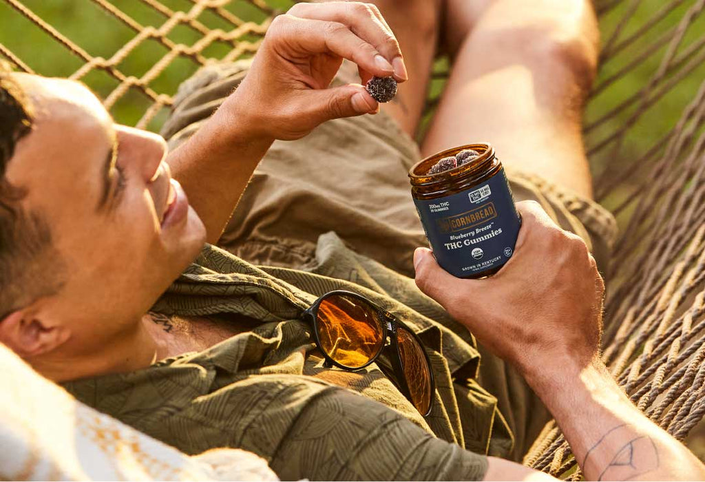 Person enjoys Cornbread Hemp THC gummies laying in a hammock.