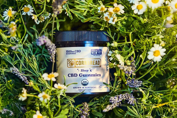 Jar of CBD gummies surrounded by greenery and flowers